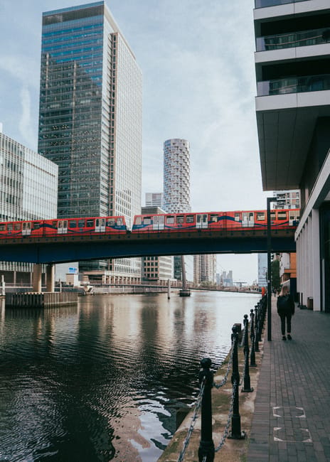A high-angle view of a modern city skyline in London, featuring tall glass office buildings with reflective surfaces and contemporary architectural designs. The scene is illuminated by natural dayligh